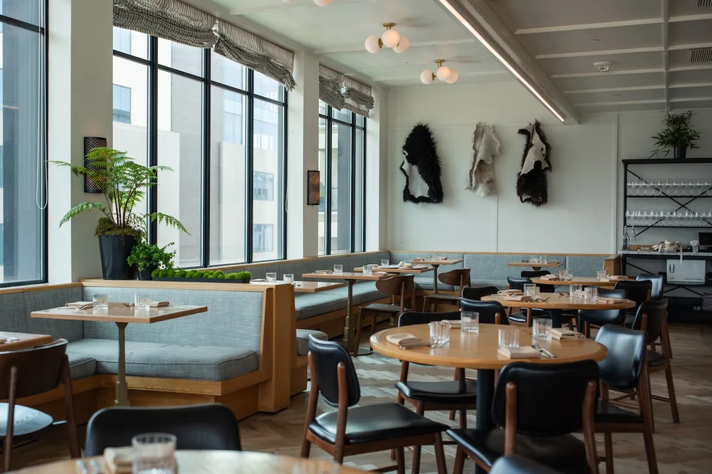 The Sheep dining room with banquettes, wood tables and sheepskins hung on the wall