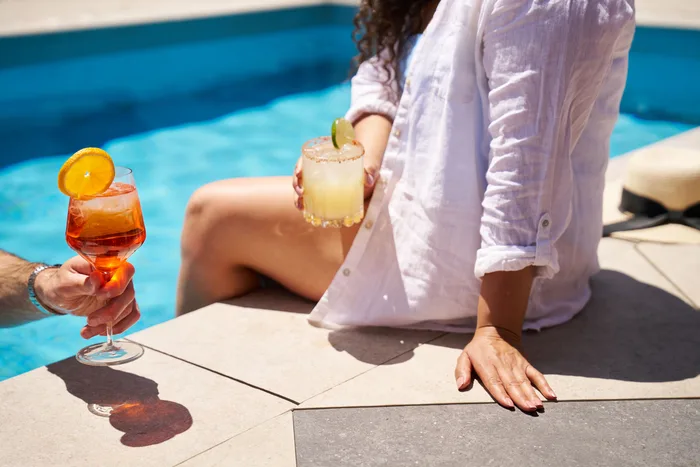 A guest with a spritz beside the rooftop pool at Clayton
